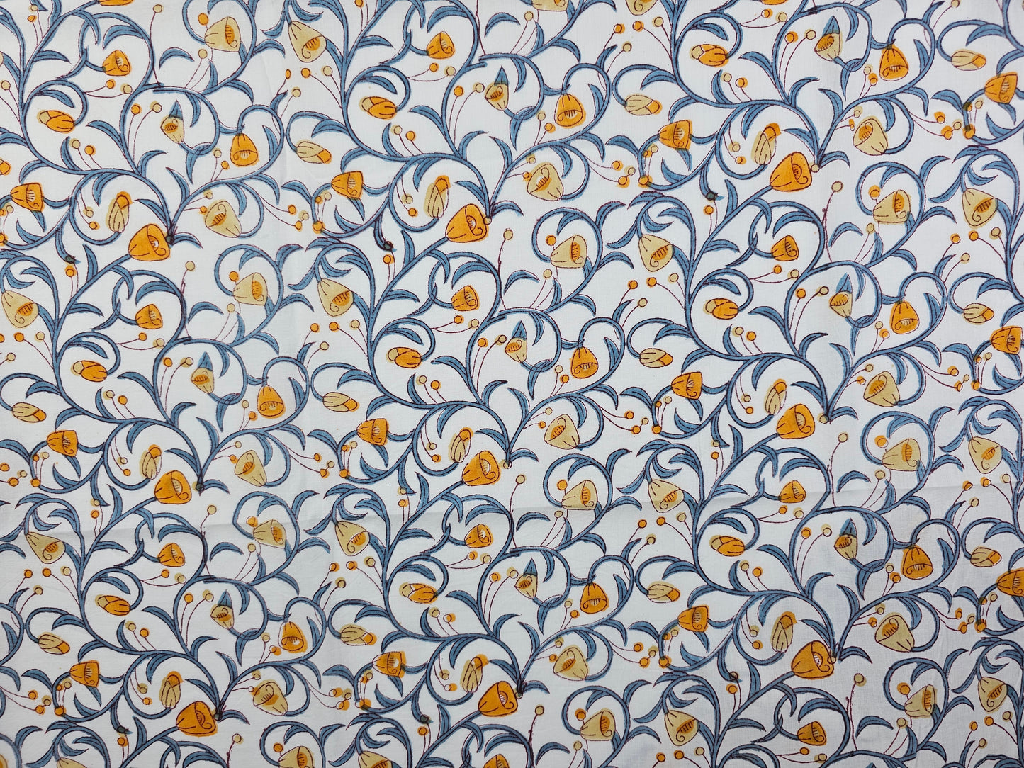 A hand printed floral pattern featuring orange and yellow flowers with blue scrolling vines on a white background.