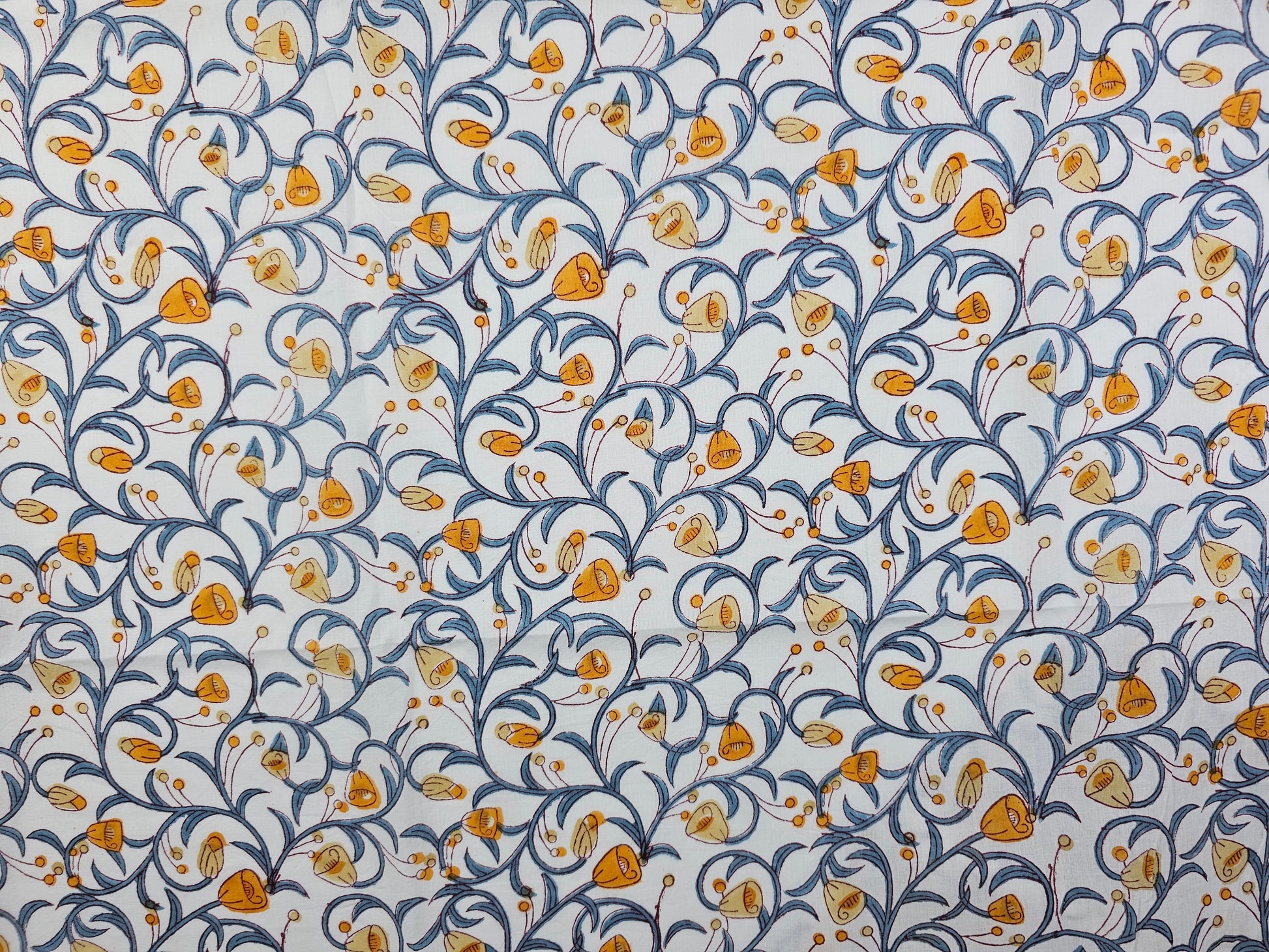 A hand printed floral pattern featuring orange and yellow flowers with blue scrolling vines on a white background.